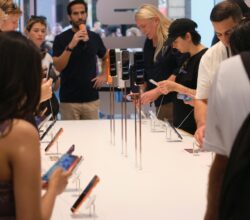 People examining smartphones displayed on a table.