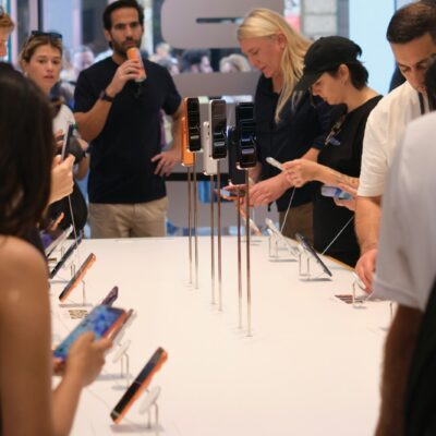 People examining smartphones displayed on a table.